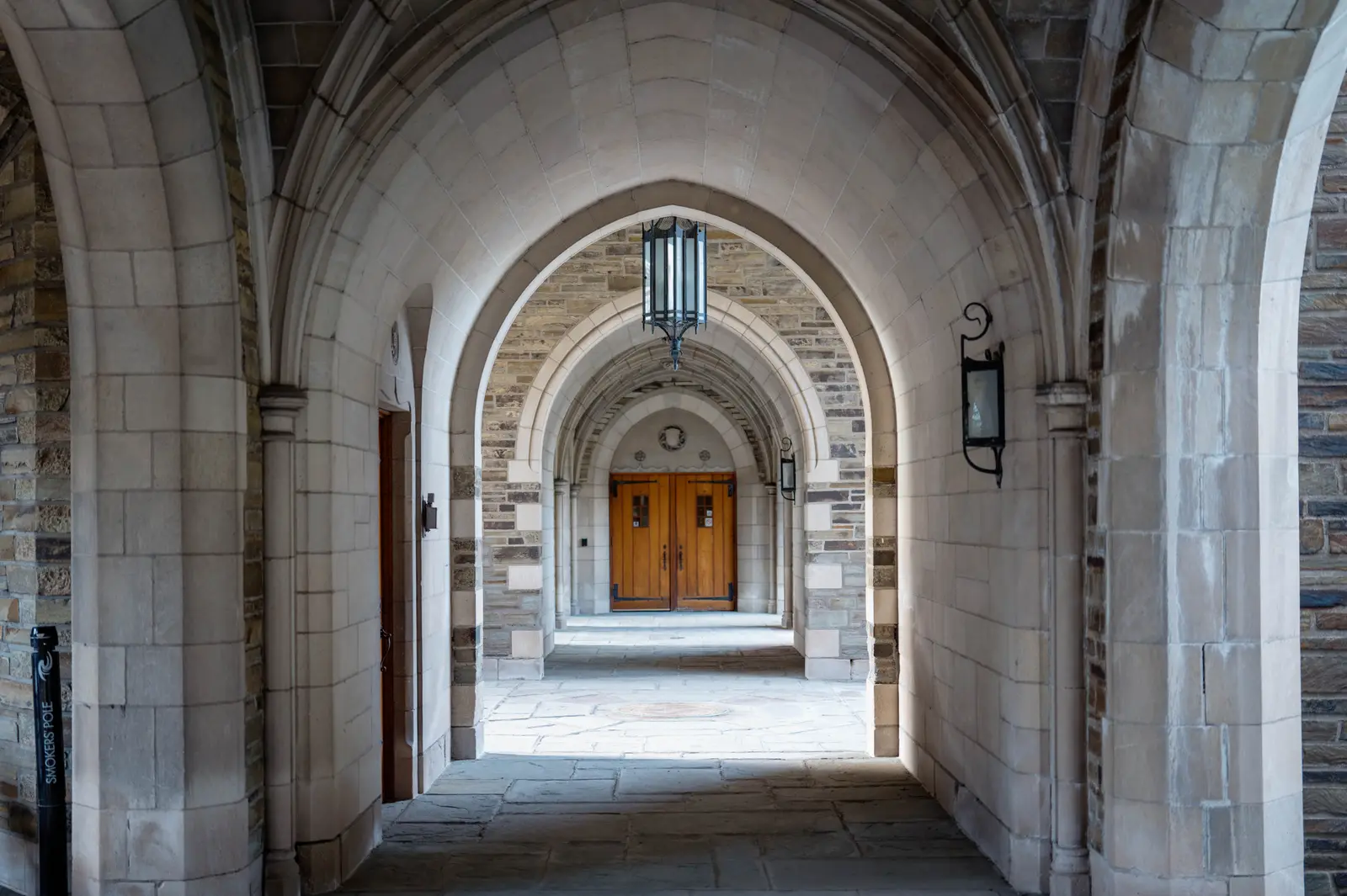A vaulted stone archway leading to a wooden door in a university building